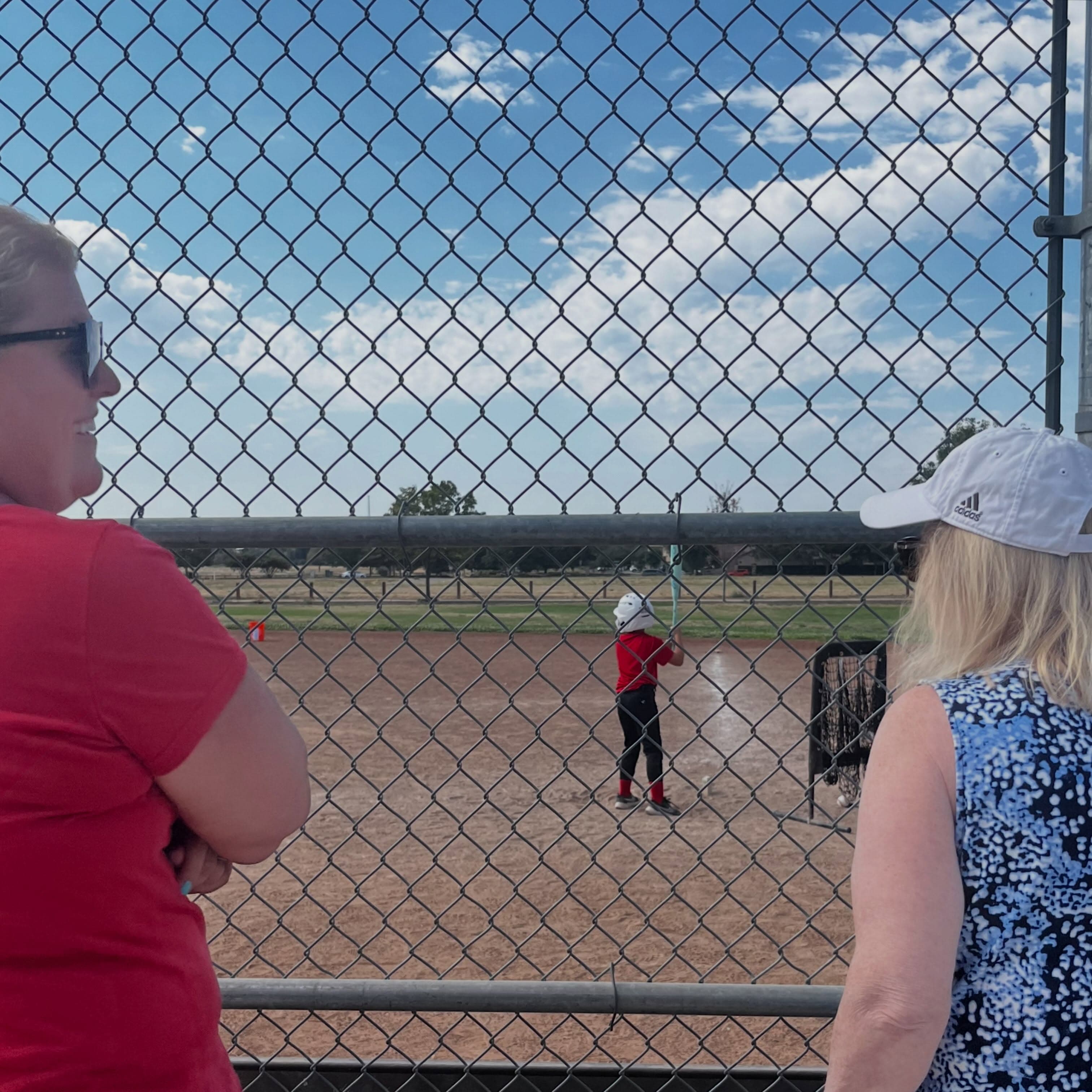 Families watch a player take swings on the field at Wild Rose Park.